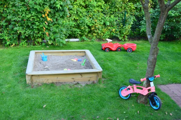 Sandkasten mit Bobbycar und Laufrad im Garten der Tagesmutter in Ratzeburg